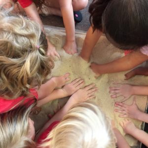 childrens' hands in sand